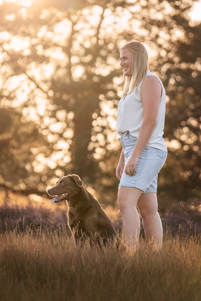 Foto von Lisa Werner Fotografie, Hund und Mensch, Frau steht neben einem Labrador im Sonnenuntergang