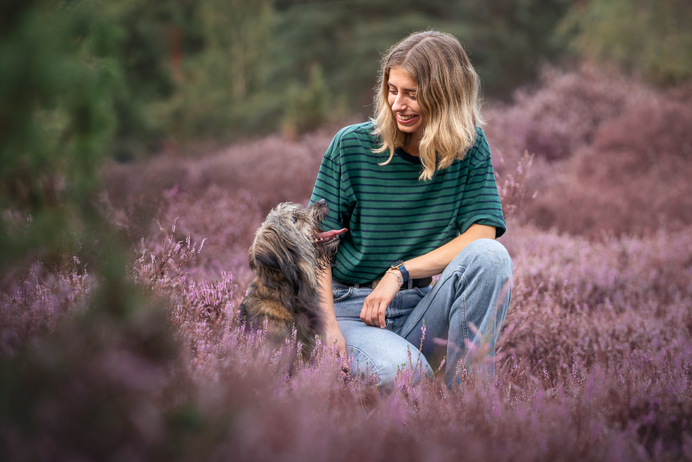 Foto von Lisa Werner Fotografie, Hund und Mensch, Frau sitzt neben einem Hund in lila Heideblüten