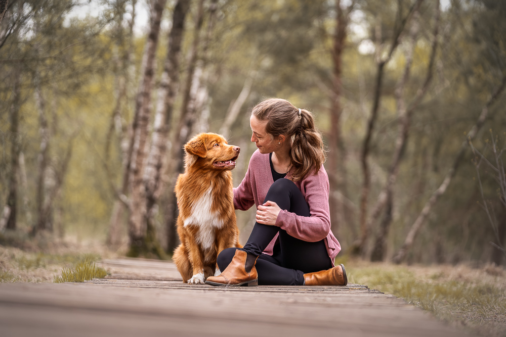 Foto von Lisa Werner Fotografie, Hund und Mensch, Frau und Nova Scotia Duck Tolling Retriever sitzen auf einem Holzweg