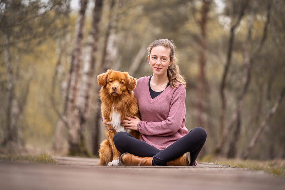 Foto von Lisa Werner Fotografie, Hund und Mensch, Frau und Nova Scotia Duck Tolling Retriever sitzen auf einem Holzweg