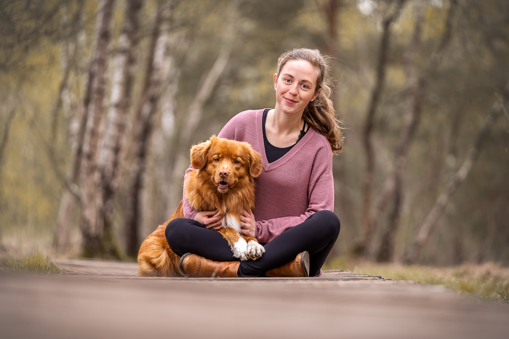 Foto von Lisa Werner Fotografie, Hund und Mensch, Frau und Nova Scotia Duck Tolling Retriever sitzen auf einem Holzweg