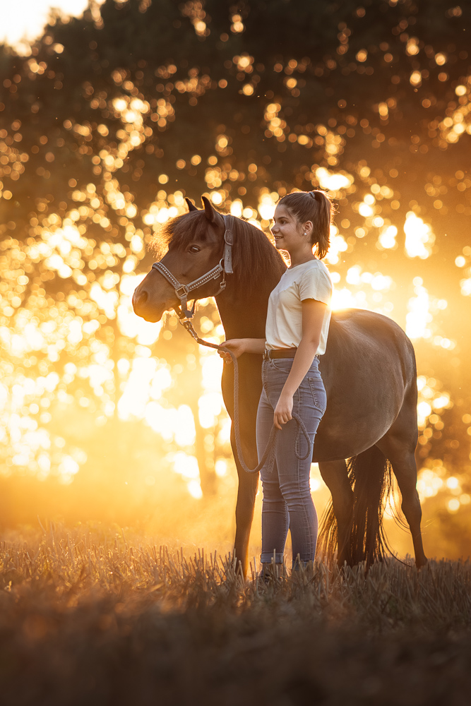 Foto von Lisa Werner Fotografie, Pferd und Mensch, Pony und Mädchen stehen auf einem Feld im Sonnenuntergang